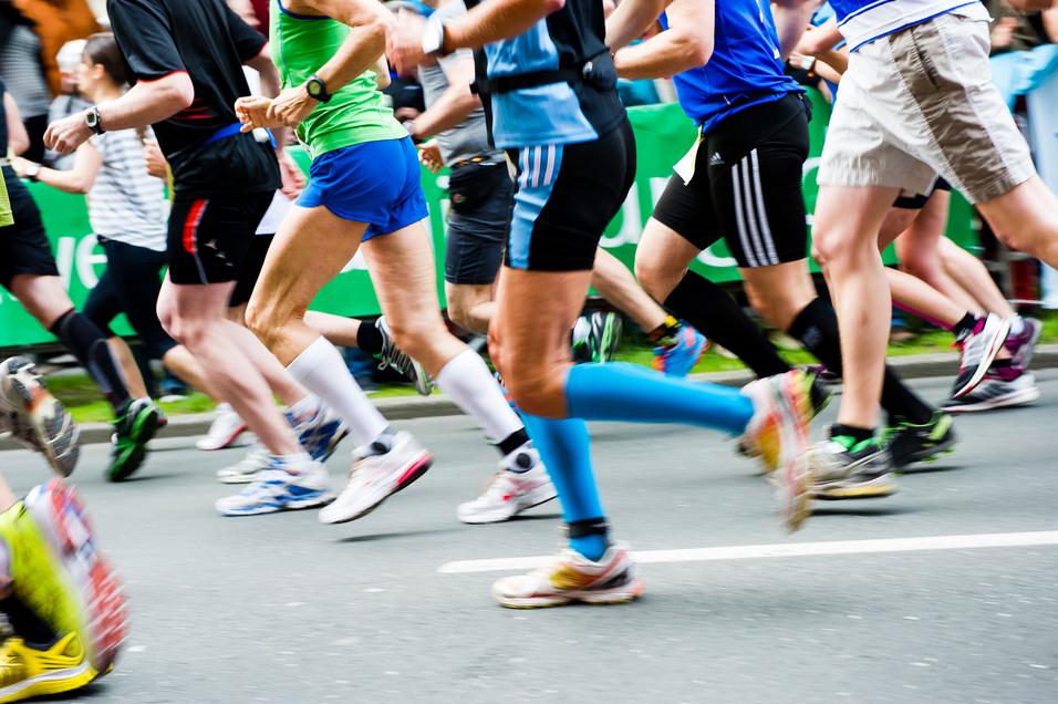 Bunte Laufschuhe rennen in einem Marathon, während Zuschauer im Hintergrund auf der Strecke stehen.